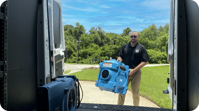 water-damage-restoration-tech-carrying-dehumidifier-to-truck